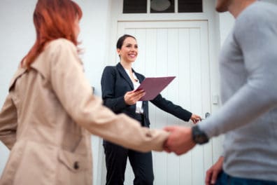 Realtor walk through the door with a couple