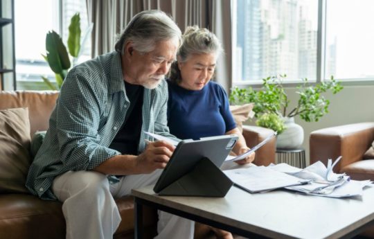 Asian American couple in their living room completing business
