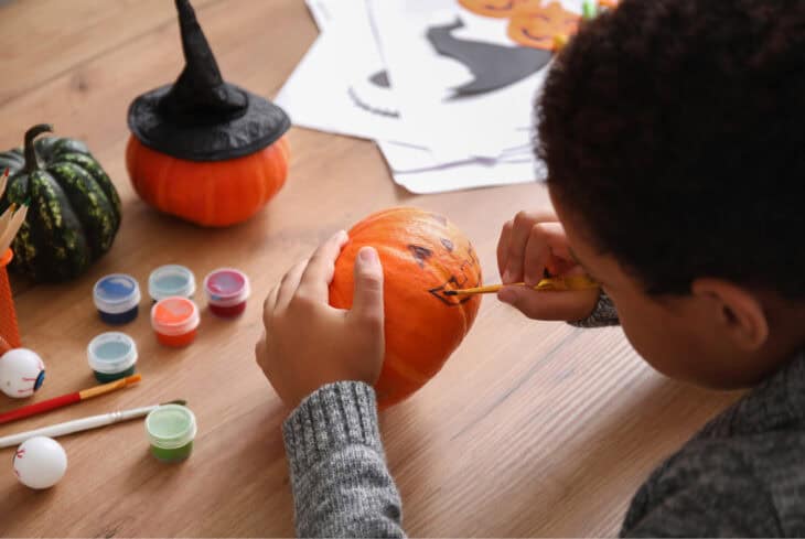 A young boy paints a pumpkin