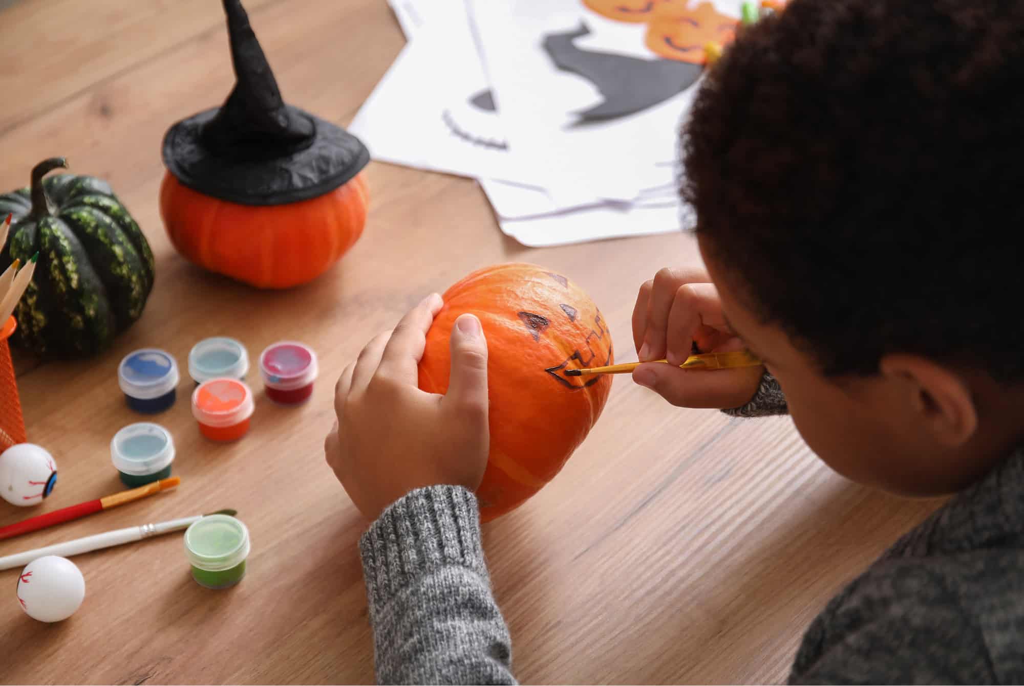 A young boy paints a pumpkin