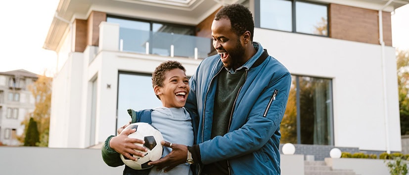 Father and young son play soccer in their front yard