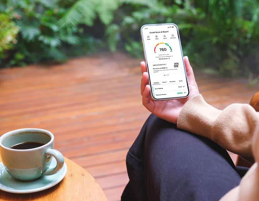 A woman sitting on her back porch with a fresh hot coffee using the SavvyMoney Credit Score tools provided by Lafayette Federal Credit Union's online banking mobile app.