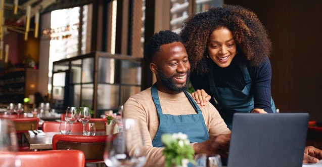 Small business owners using laptop in restaurant