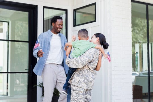 Family carrying American flags are happy to see soldier mom