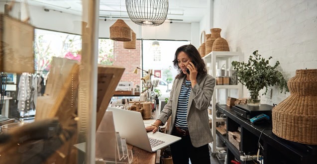 Smiling Asian woman talking on a cellphone in her store