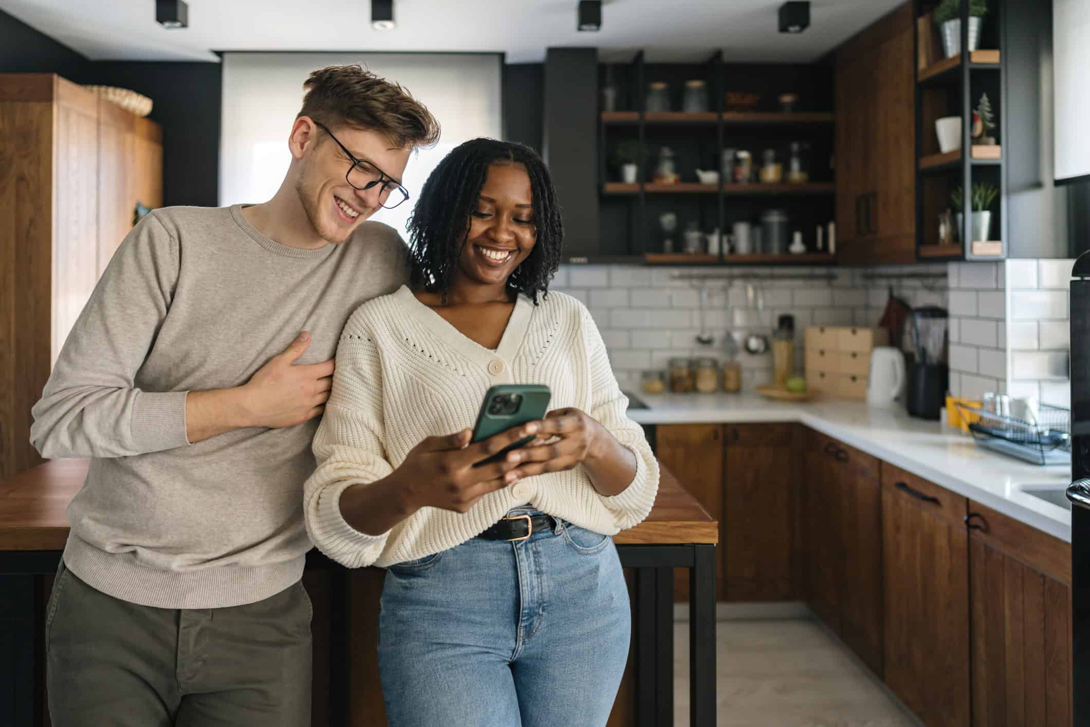 Happy couple using phone in kitchen