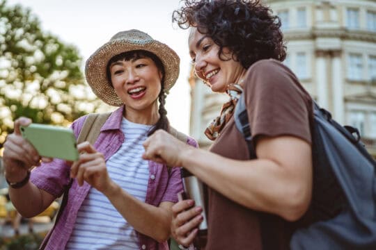 Two women in a city happily reading through the Lafayette Federal Credit Union member welcome kit.