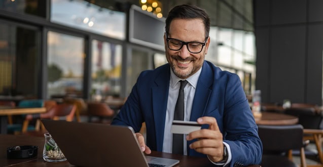 Businessman making online payment using credit card and laptop in cafe