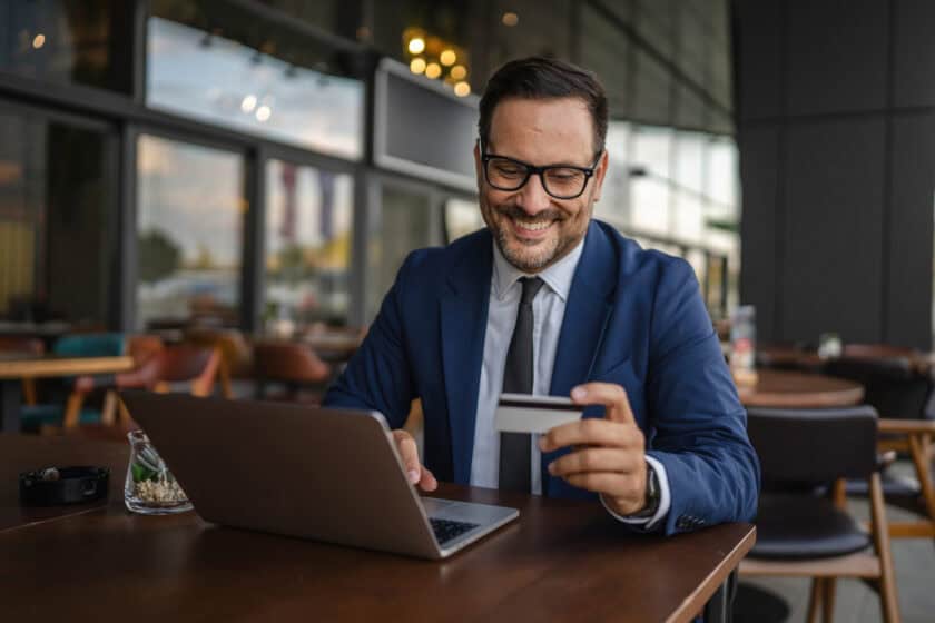 Businessman making online payment using credit card and laptop in cafe