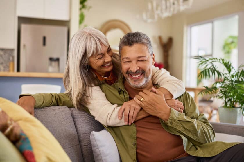Funny retired multiethnic couple hugging and laughing